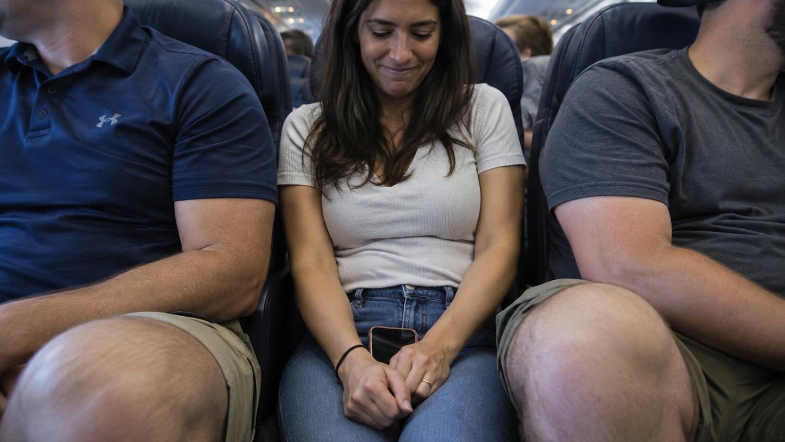 Elle publie une photo d'elle assise entre deux hommes en classe éco : un détail déclenche une vague d'indignation