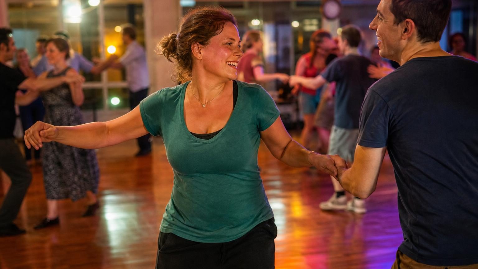 Une personne souriante en tenue de danse, le visage rougi après l'effort, quittant une salle de cours avec enthousiasme.