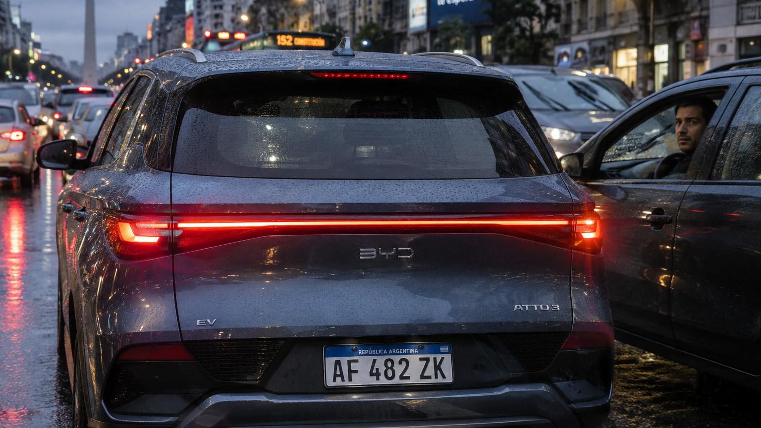 Lunette arrière verticale d'un SUV électrique chinois moderne, très lisse et épurée, sans essuie-glace visible, avec gouttelettes d'eau accumulées.