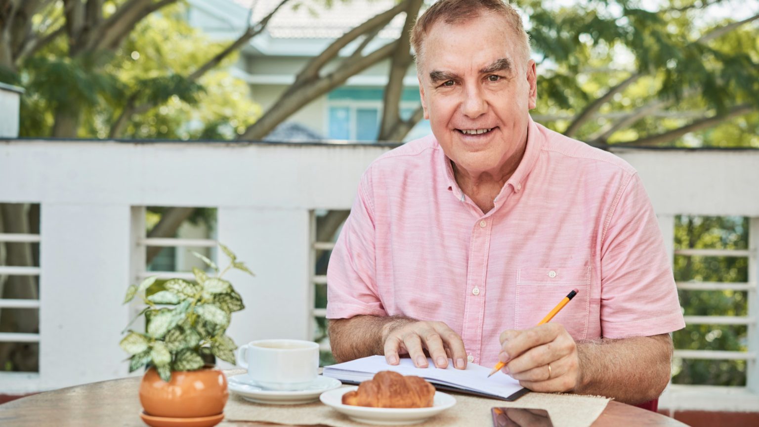 Un homme d'âge mûr seul dans une cuisine silencieuse le matin, regardant pensif son téléphone, incarnant le sentiment de vide et de désorientation des premiers mois de retraite.