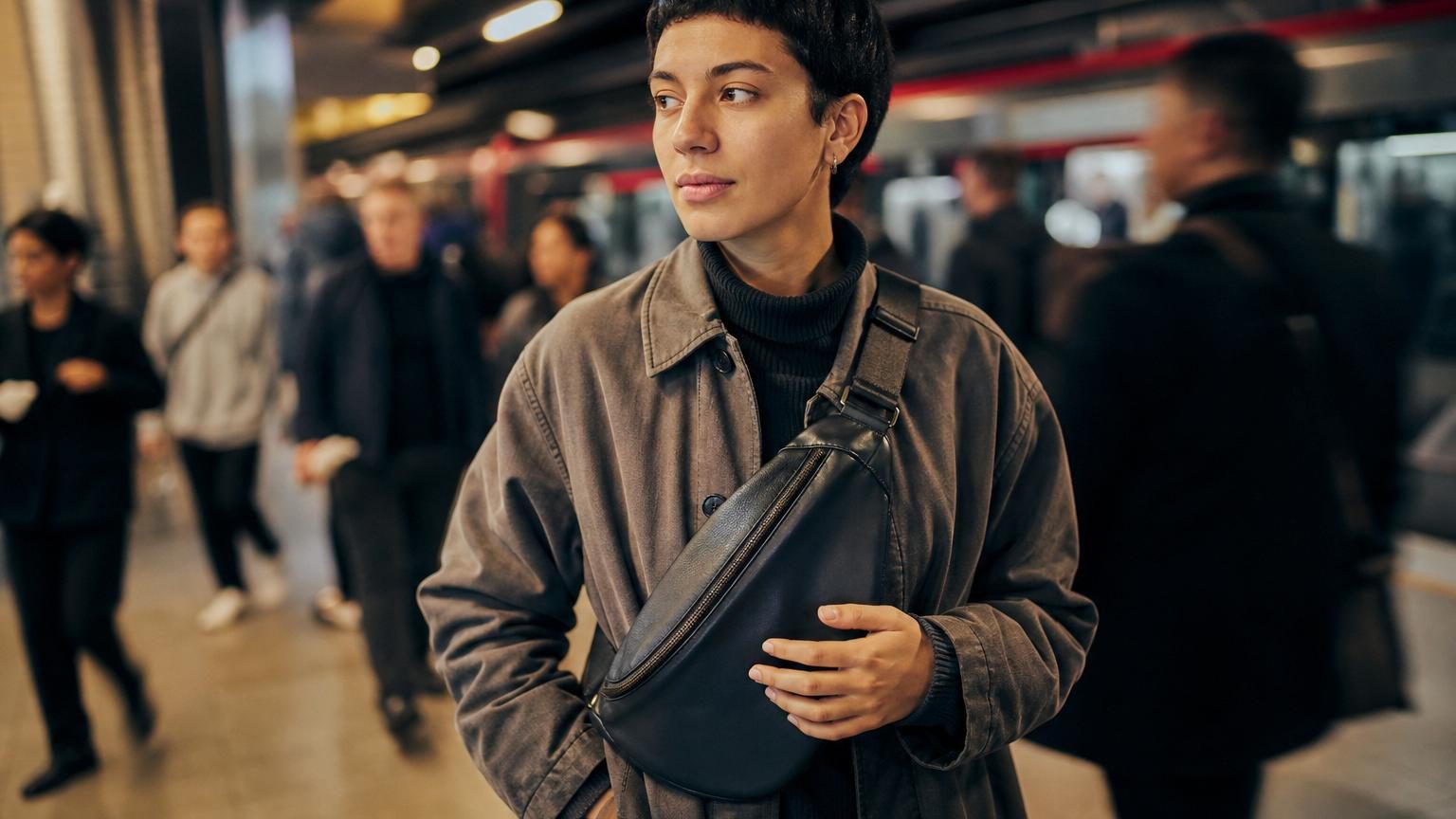 Personne marchant dans la rue ou les transports avec un sac en bandoulière porté contre le buste, les mains libres