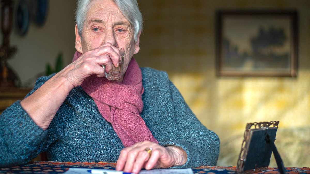 Une femme âgée feuillette son relevé de carrière et ses notes de dépenses, reflet de l'inquiétude des retraités face au montant minimal de leur pension en 2026